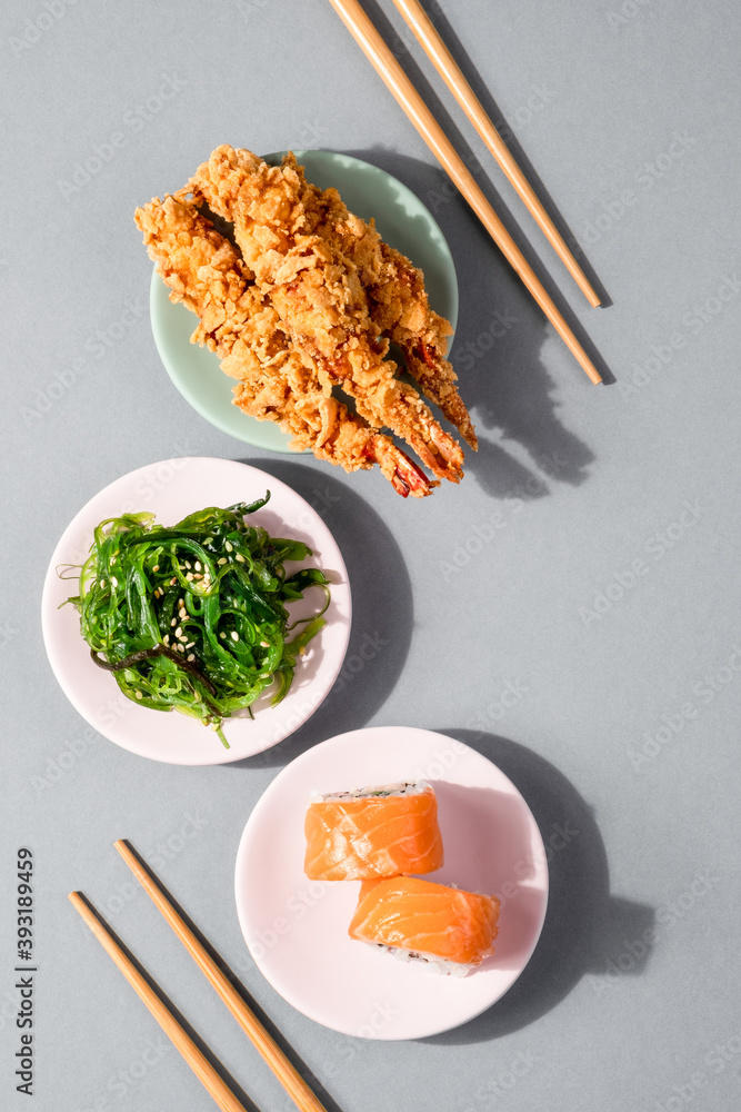 灰色背景下的日本美食创意布局。费城寿司卷配三文鱼沙