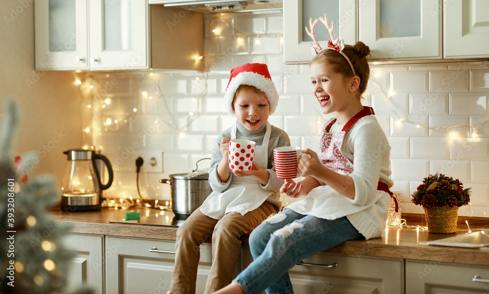 happy children on Christmas eve,   girl and boy drink hot cocoa drink that they baked together in co