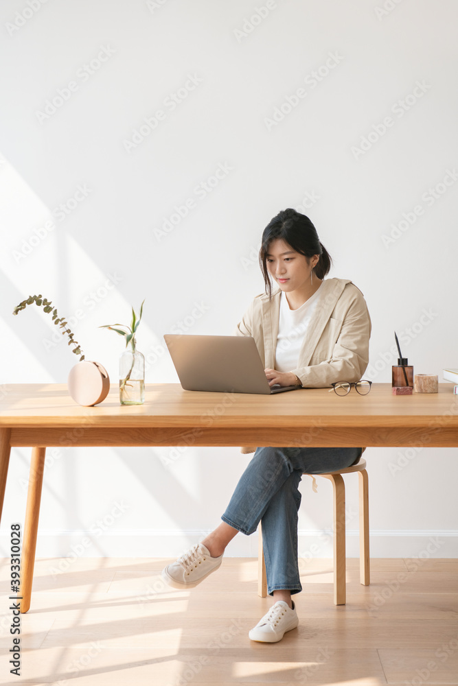 Happy Asian woman working at home using a laptop