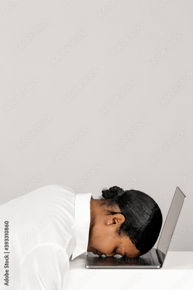 疲惫的黑人妇女把头靠在笔记本电脑上