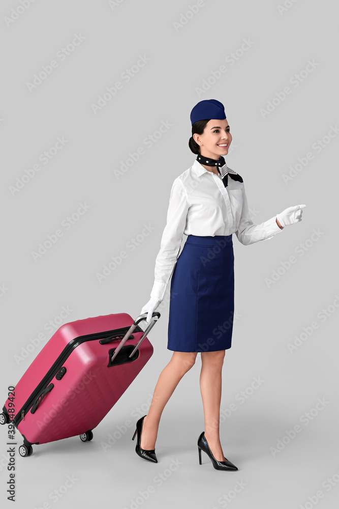 灰色背景带行李的漂亮空姐