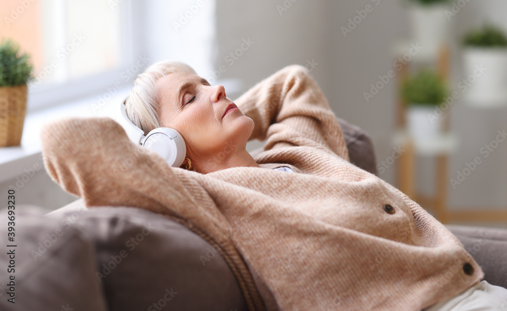 躺在沙发上听音乐的老年妇女。