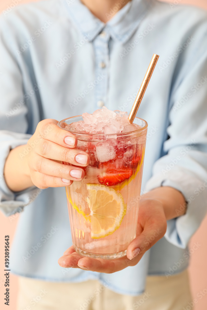 女人拿着一杯彩色背景的新鲜草莓柠檬水，特写镜头