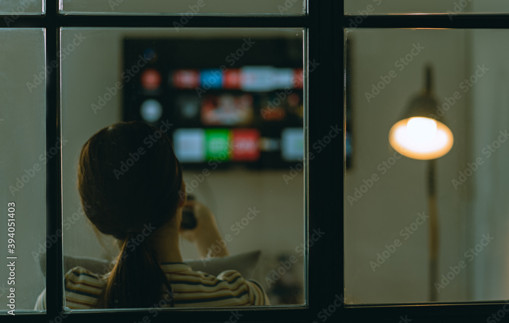 亚洲女人晚上独自坐在沙发上看电视的模糊画面