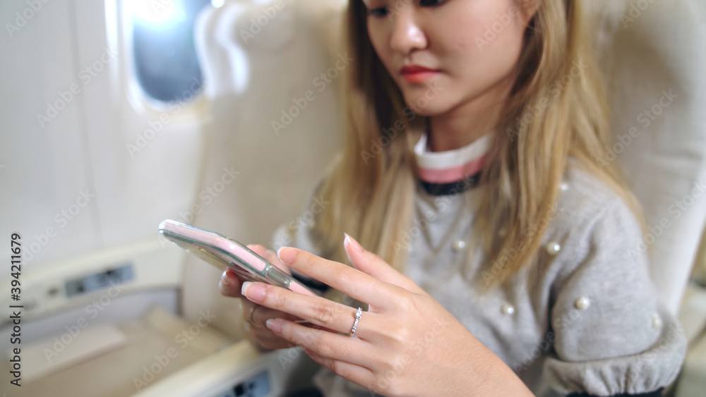 亚洲女性在飞机上使用手机。旅行和互联网连接概念。