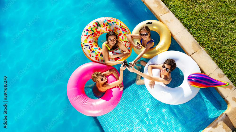 一群孩子在游泳池里用充气玩具甜甜圈从上面喝苏打水