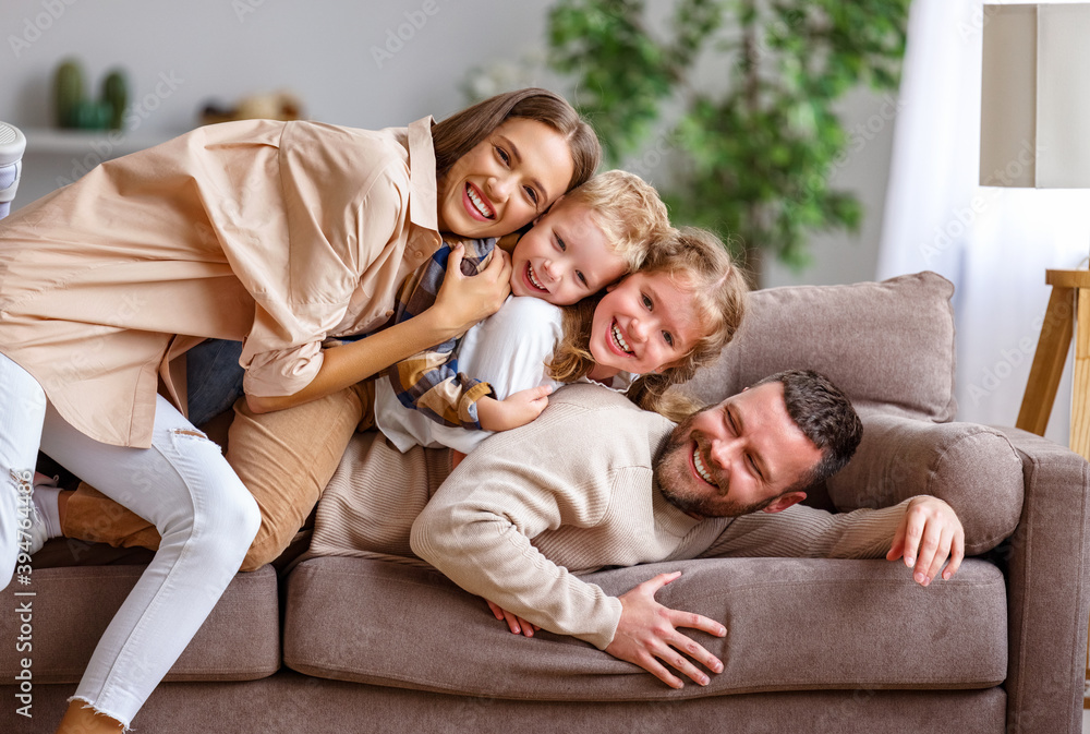 幸福的家庭母亲父亲和孩子们在家里的沙发上玩得很开心。