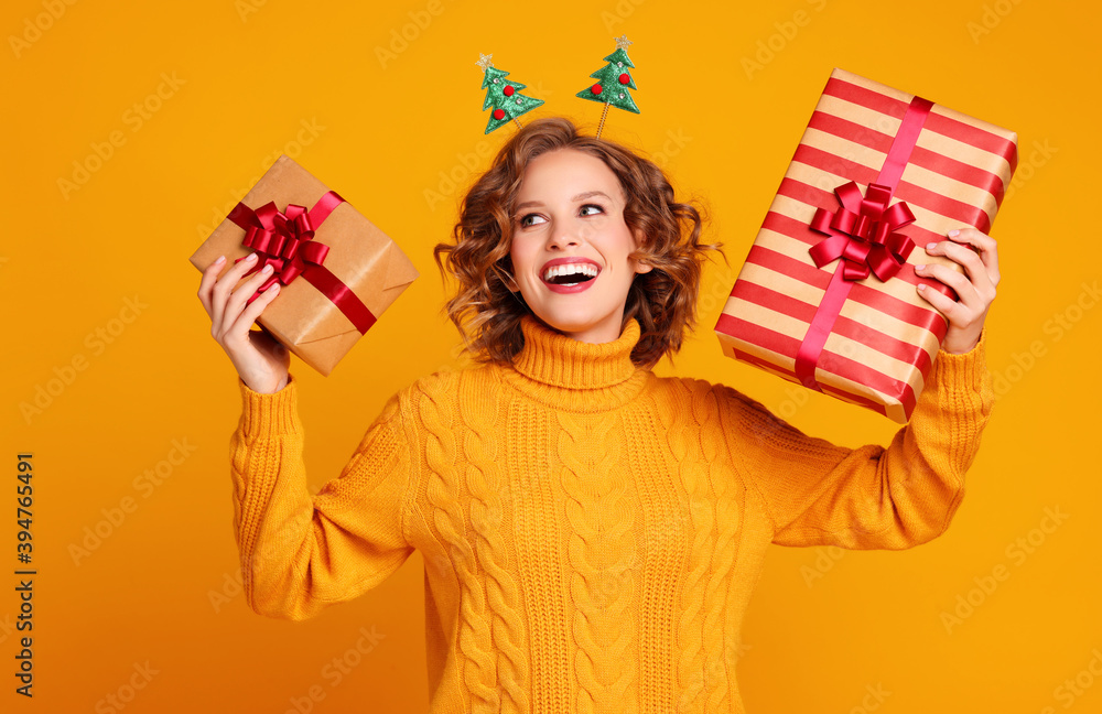 一个快乐而惊讶的女人张着嘴笑着，手里拿着黄色b色的圣诞礼物