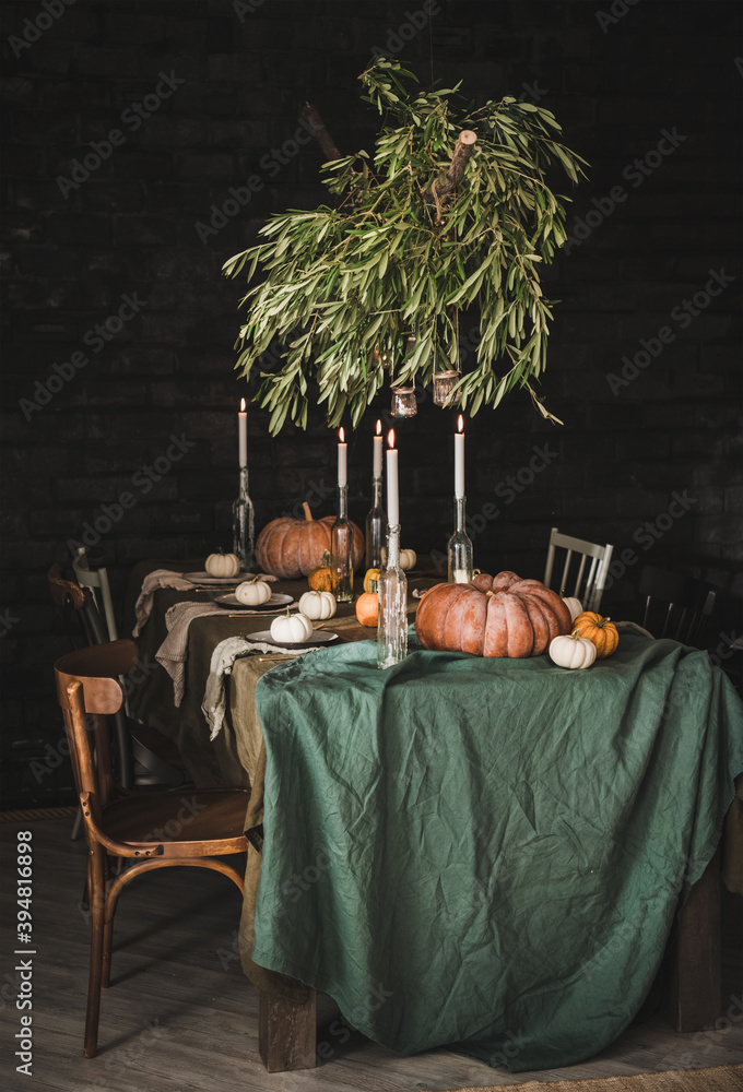 时尚的乡村感恩节派对餐桌设置。绿色亚麻桌布的实心餐桌，晚餐