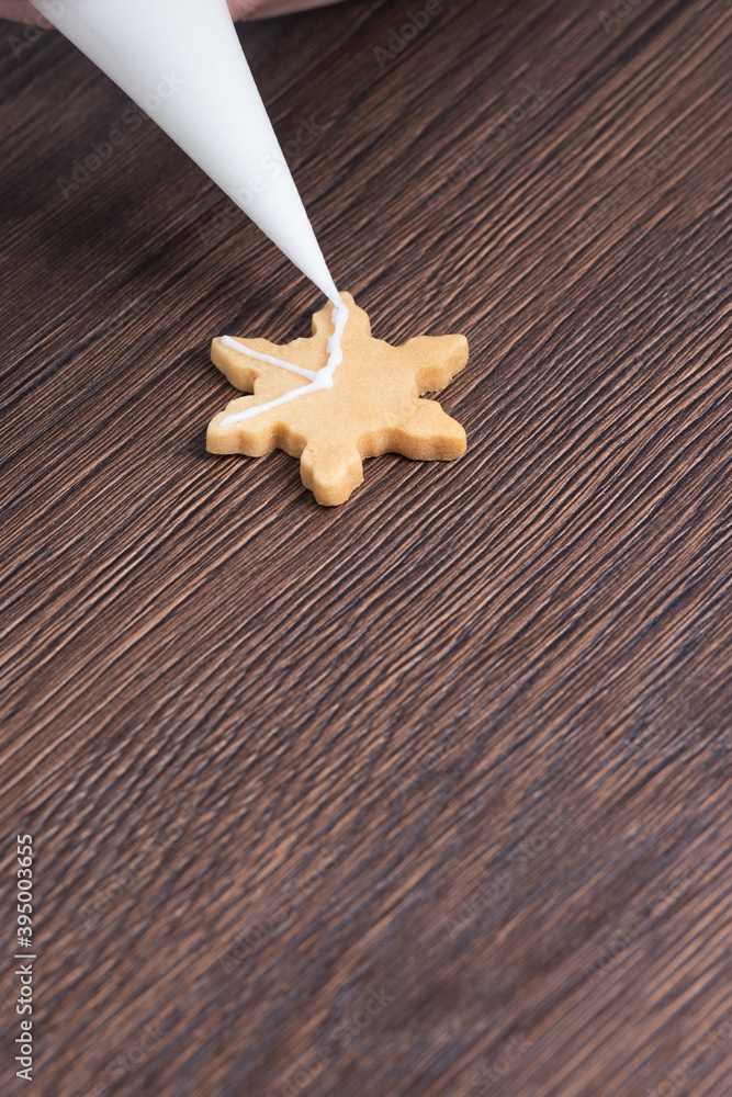用糖霜在木桌背景上绘制圣诞雪花糖饼干的特写。