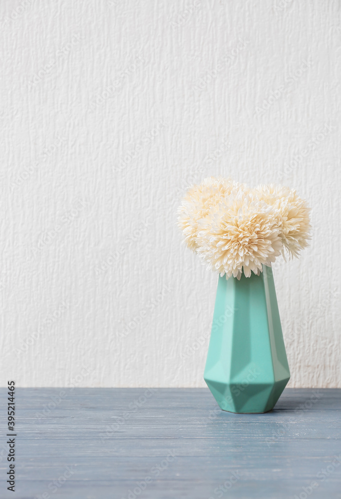 Beautiful vase with chrysanthemums on table against white background