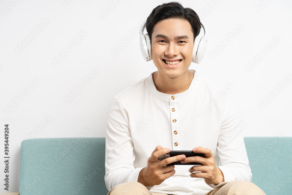 亚洲男子戴着无线耳机在手机上玩游戏