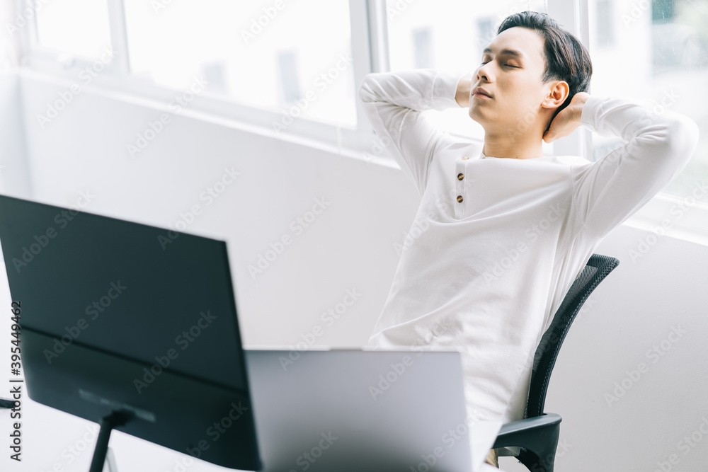 亚洲程序员在劳累的工作时间后，头靠在椅子上放松