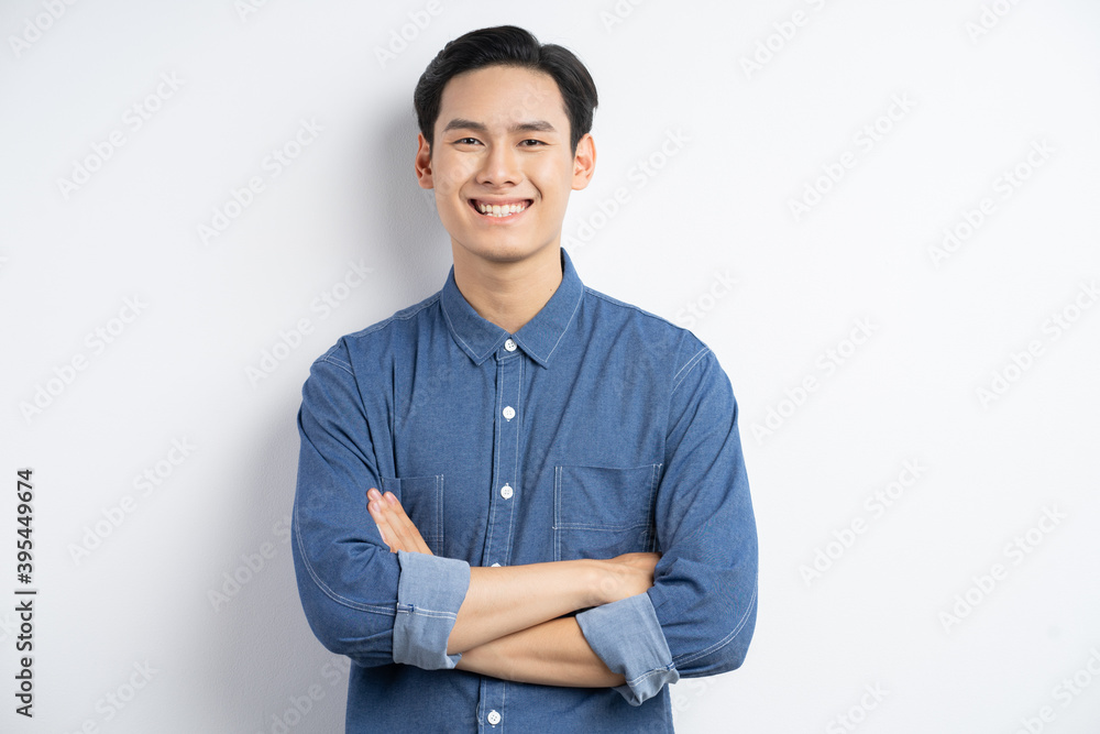 一名亚洲男子交叉双臂站在白色背景上微笑的照片