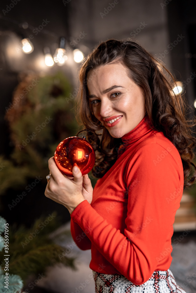 快乐的年轻女人在圣诞树前举着圣诞球。新年和寒假公关