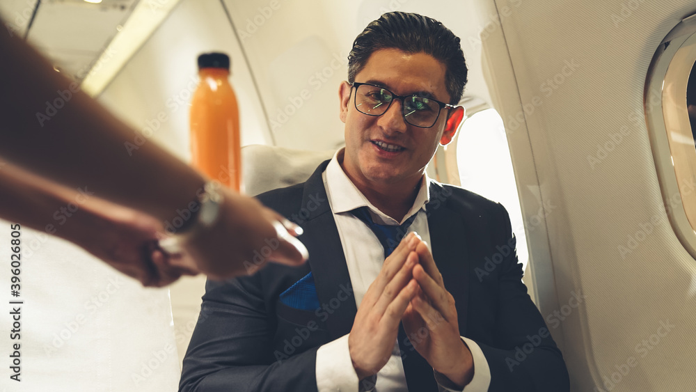 Businessman have orange juice served by an air hostess in airplane . Business trip travel concept .