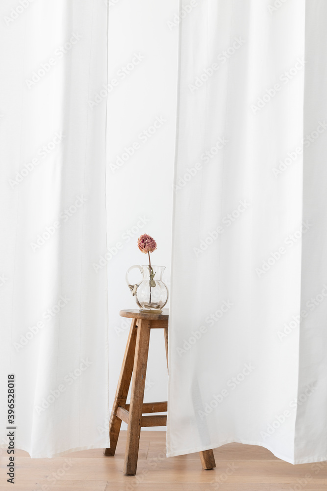 白色房间木凳上的玻璃罐里的干牡丹花
