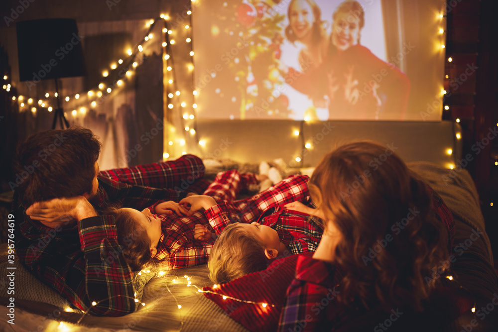圣诞节晚上，家庭母亲、父亲和孩子们用爆米花观看投影仪、电视和电影