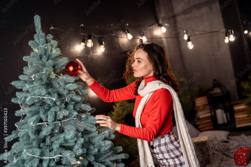 圣诞节、新年、寒假概念：年轻快乐的微笑女士装饰新年树，posi