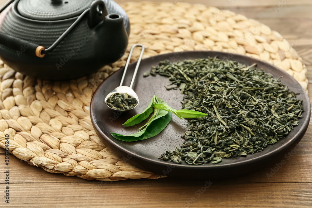 木桌上盘子里的茶壶和干绿茶