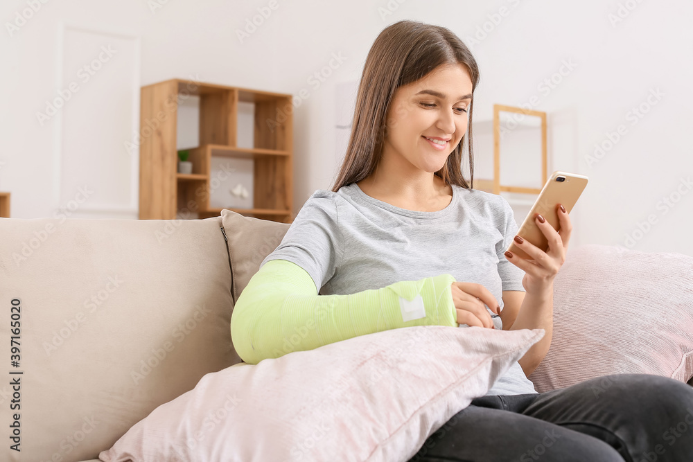 年轻的断臂妇女在家使用手机