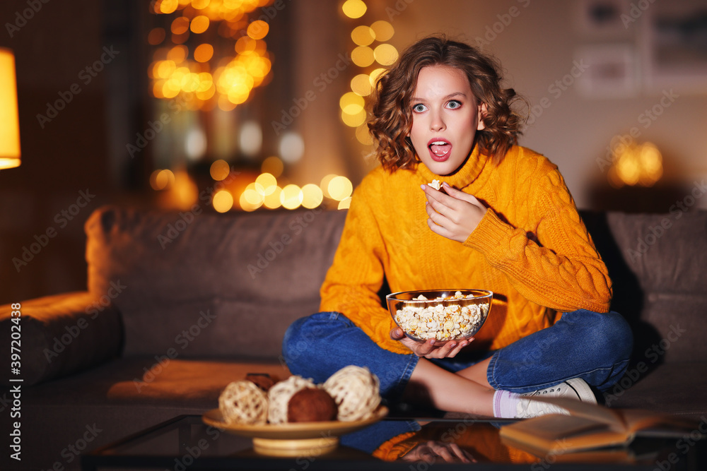 Young female eating popcorn and watching interesting movie