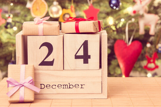 复古照片，立方体日历上的12月24日，包装好的礼物和带装饰的圣诞树