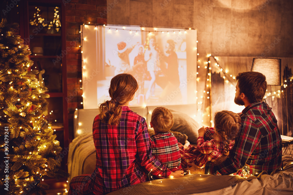 家人、母亲、父亲和孩子在圣诞节晚上用爆米花看投影仪、电影