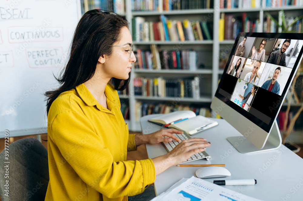 在线教育。一名女学生在家在线学习，专注于在电脑显示器上观看。