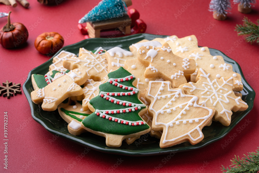 红色桌子背景的盘子里的圣诞糖饼干特写。