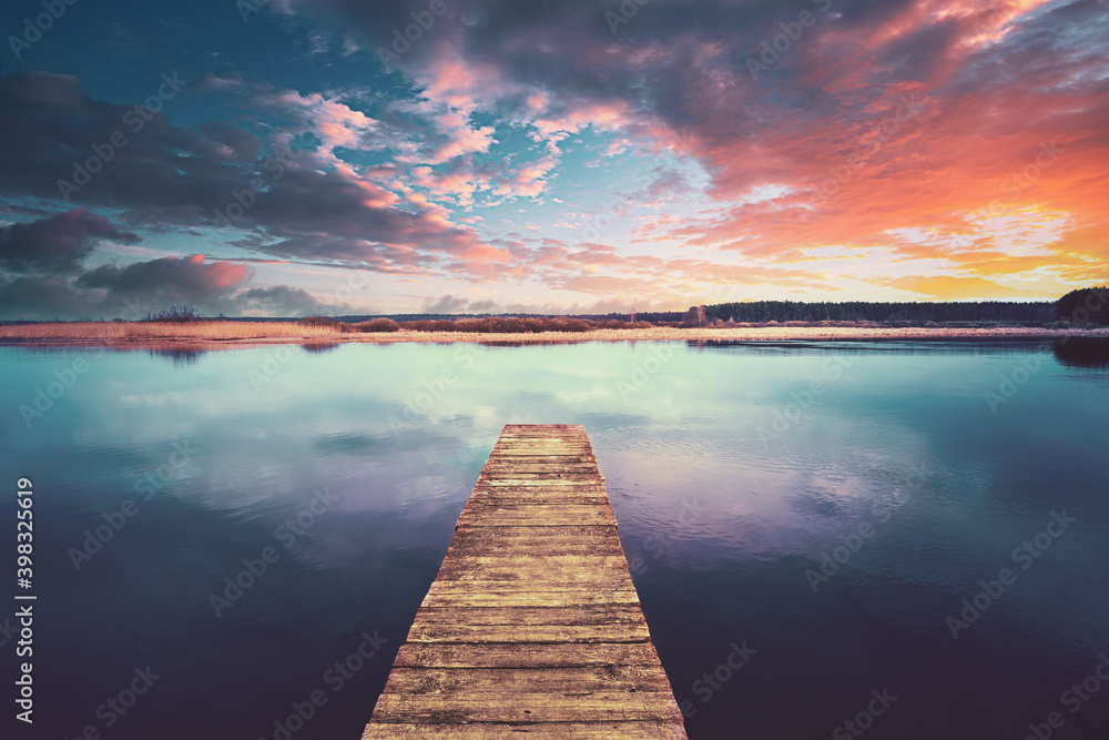 五彩缤纷的日落日出木板码头上戏剧性的天空。平静的湖水，河流。自然，