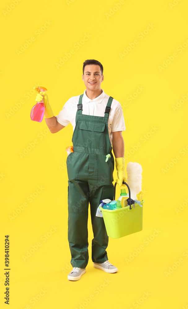 年轻的男清洁工，彩色背景上有清洁用品