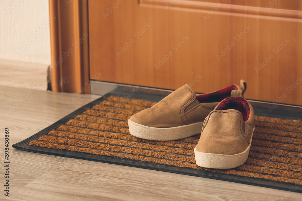 Little boy shoes near door on mat