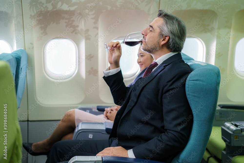 在航班上，商人乘客手持一杯起泡酒，在商务舱喝
