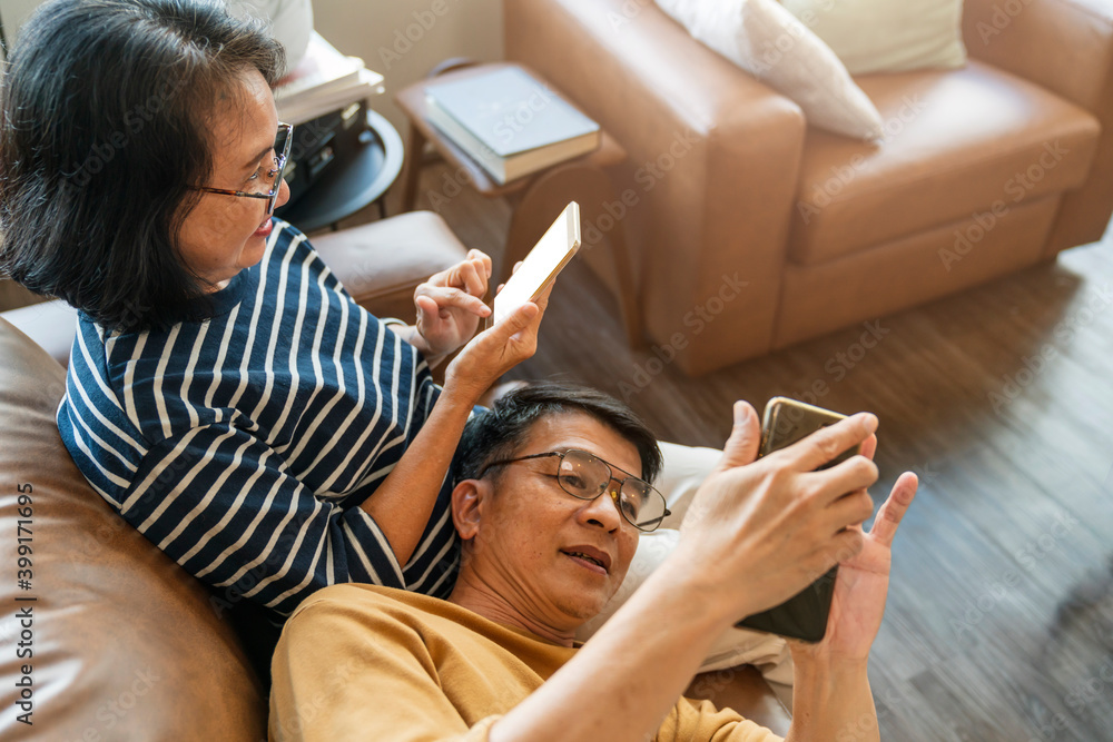 快乐的亚洲老情人夫妇拿着智能手机看着手机屏幕大笑休闲r