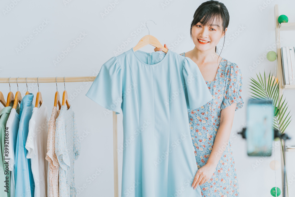 年轻的亚洲美女正在社交媒体上用智能手机直播卖衣服p