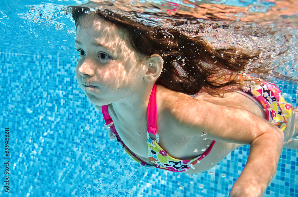 小孩在游泳池里水下游泳，快乐活泼的女婴在水下潜水，玩得很开心