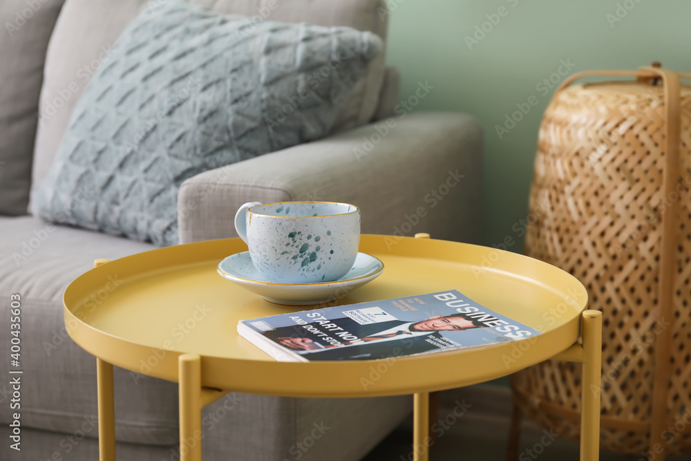 Cup and magazine on stylish table in room