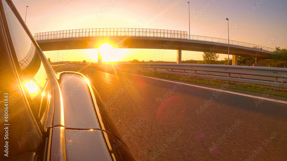特写：美丽的金色夜空笼罩着一辆在高速公路上超速行驶的汽车。