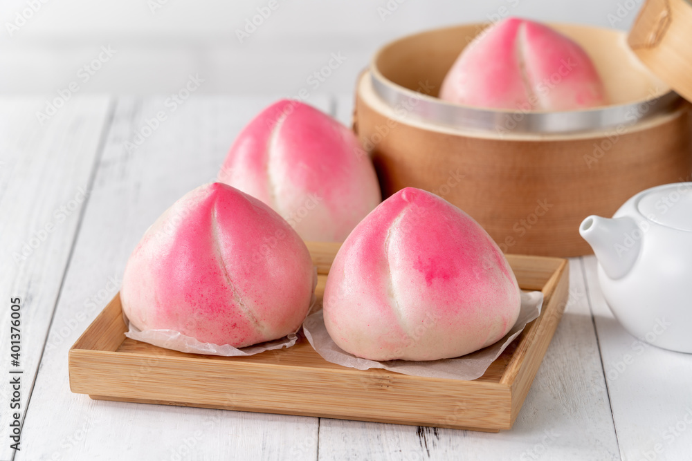 白色餐桌背景上的粉红色中国水蜜桃生日面包食品。