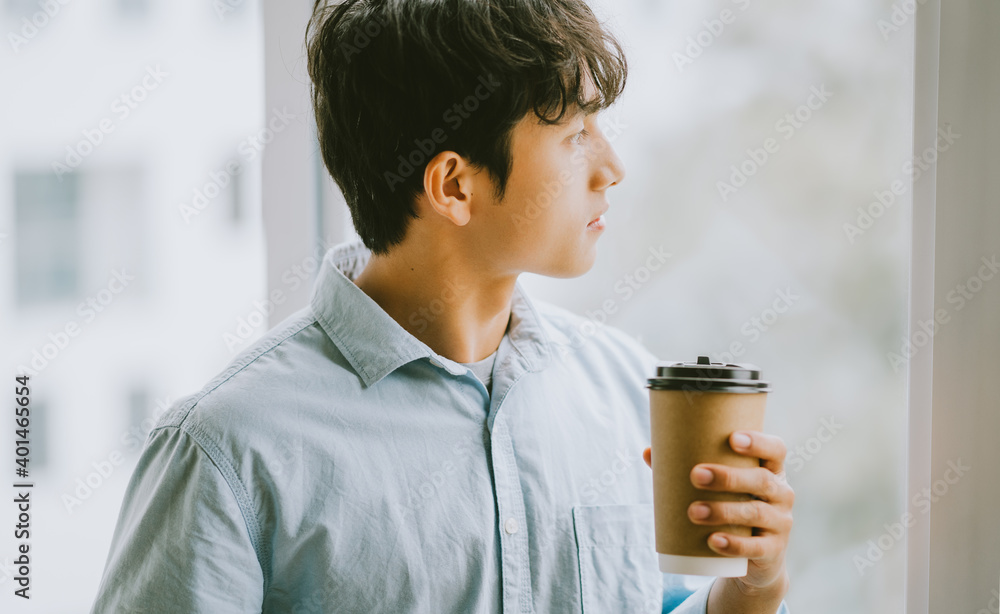 Asian businessman is drinking coffee by the window