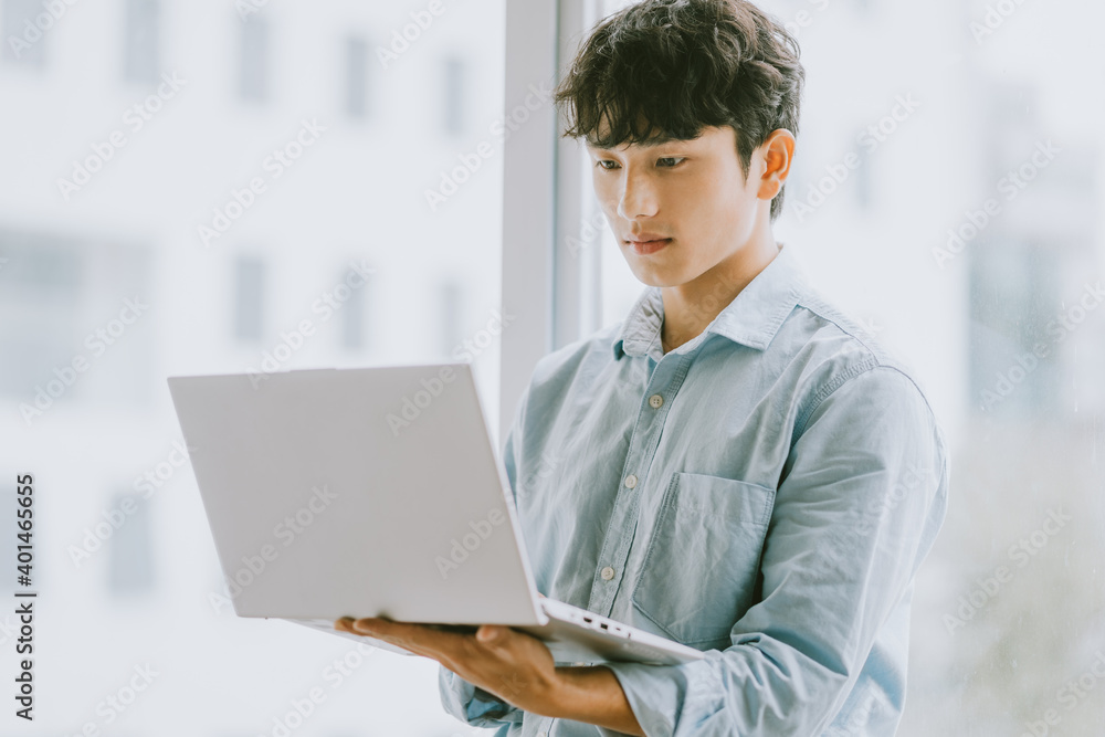 亚洲商人正在使用笔记本电脑靠窗办公