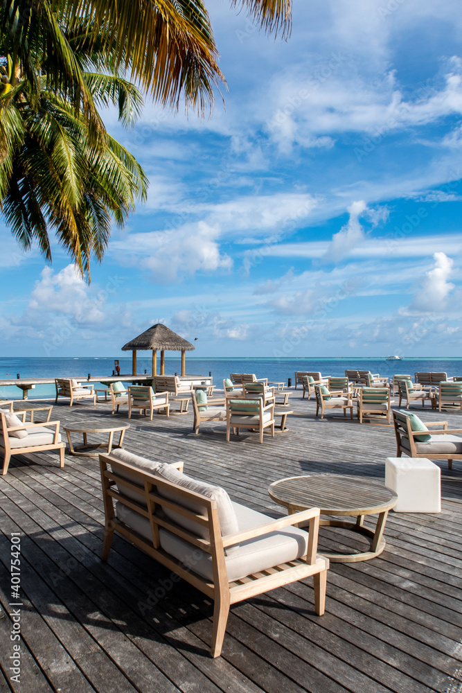 带桌子和沙发的俯瞰海洋的木制平台，热带豪华度假胜地的餐厅