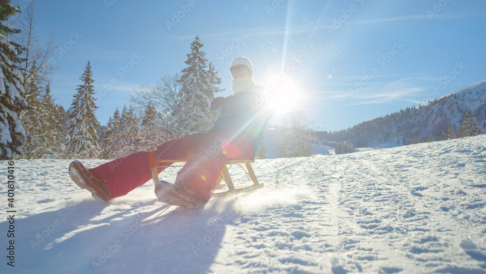 特写：一个快乐的女人正在风景如画的雪山上玩雪橇。