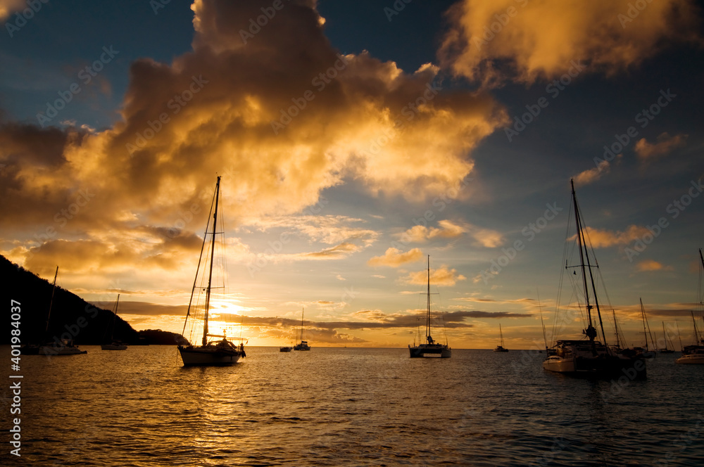 日落时在热带海湾抛锚。黄昏时在海水上停泊小型游艇和双体船。San