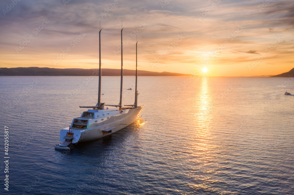 夏季日落时，蓝色大海中豪华游艇的鸟瞰图。大型现代帆船。美丽的俯视图