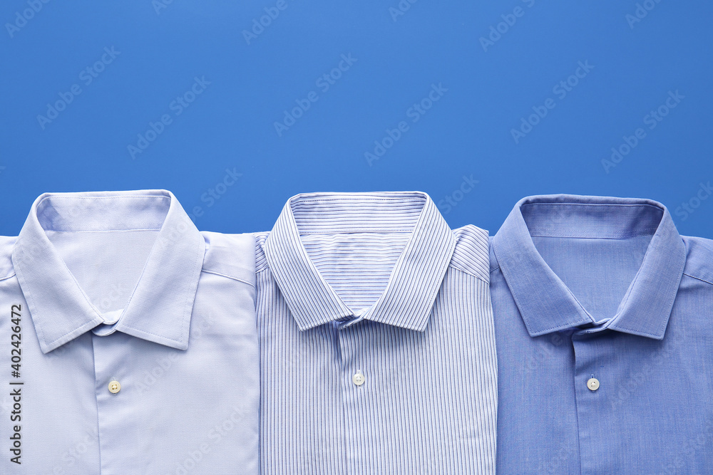 Folded male shirts on color background