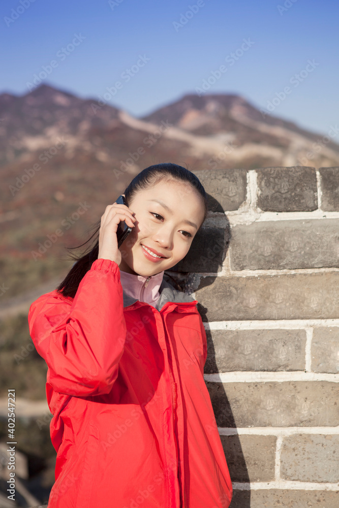 A young woman use the mobile phone in the Great Wall Tourism 