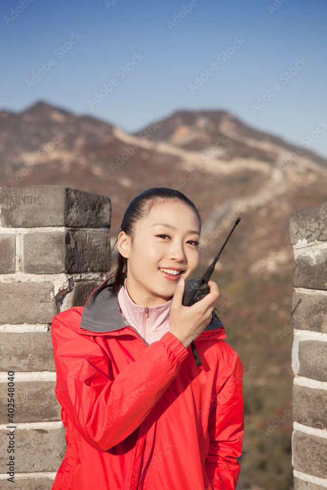 一名年轻女子在长城旅游中使用对讲机