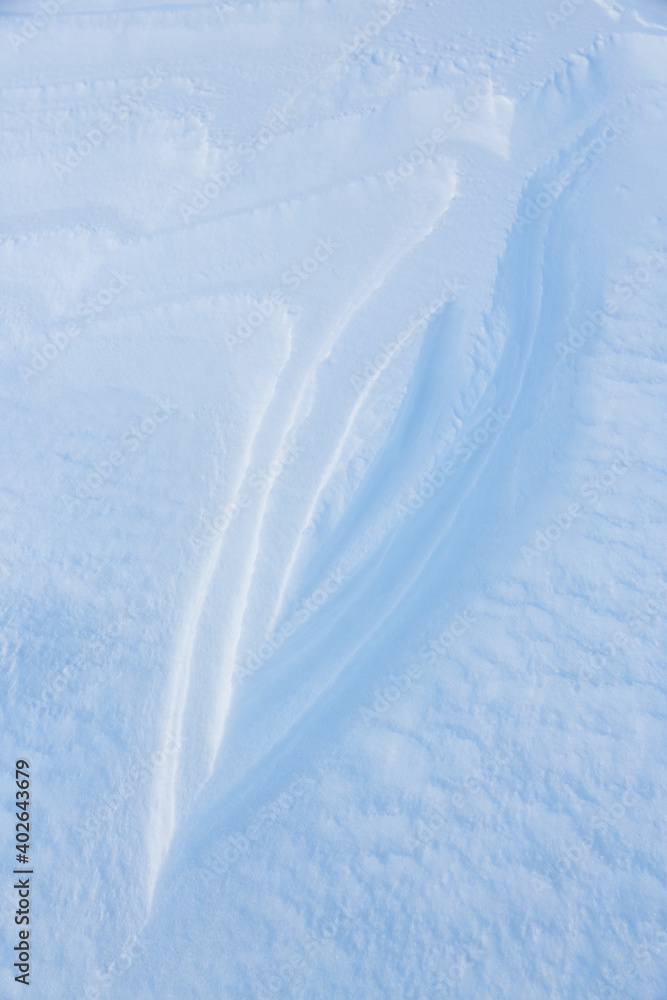 Beautiful winter background with snowy ground. Natural snow texture. Wind sculpted patterns on snow 